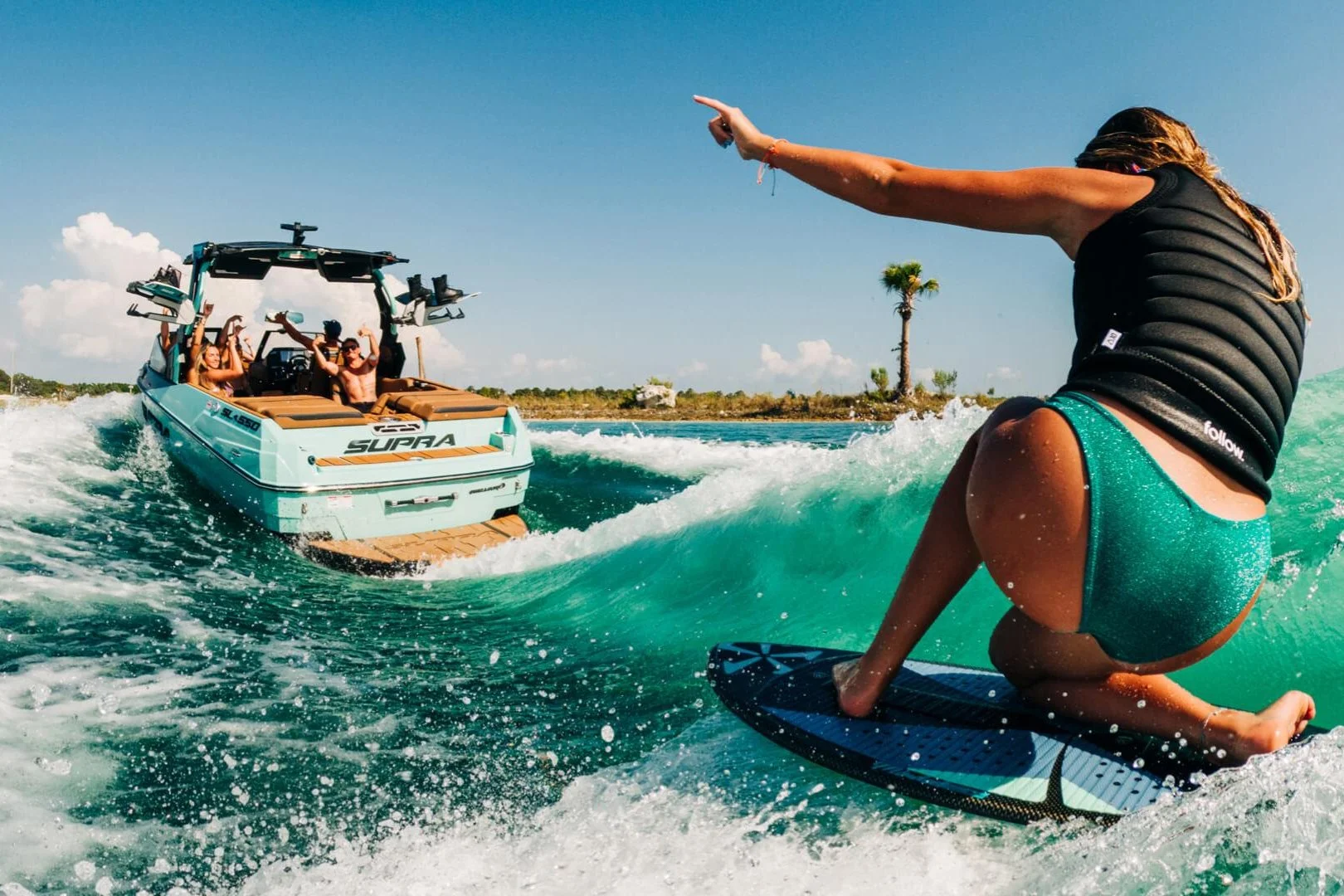 A rider surfing the wake behind the O’Town Supra boat, crew cheering
