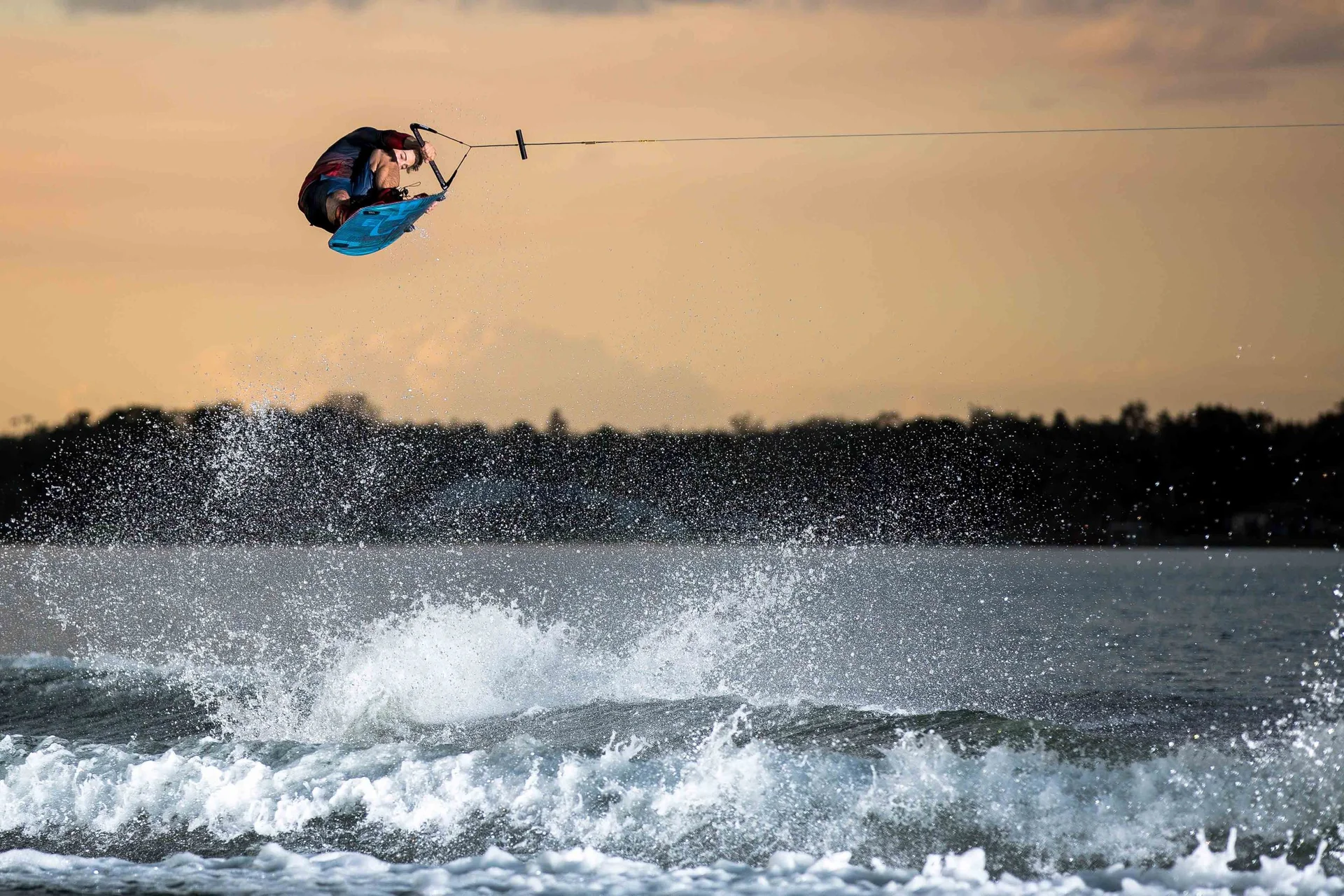 A rider inverted high above the wake at sunset