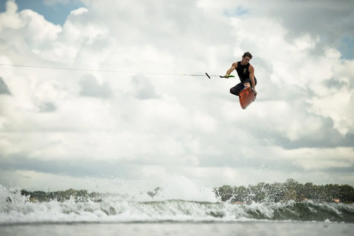 A rider high above the wake against a bright, cloudy sky