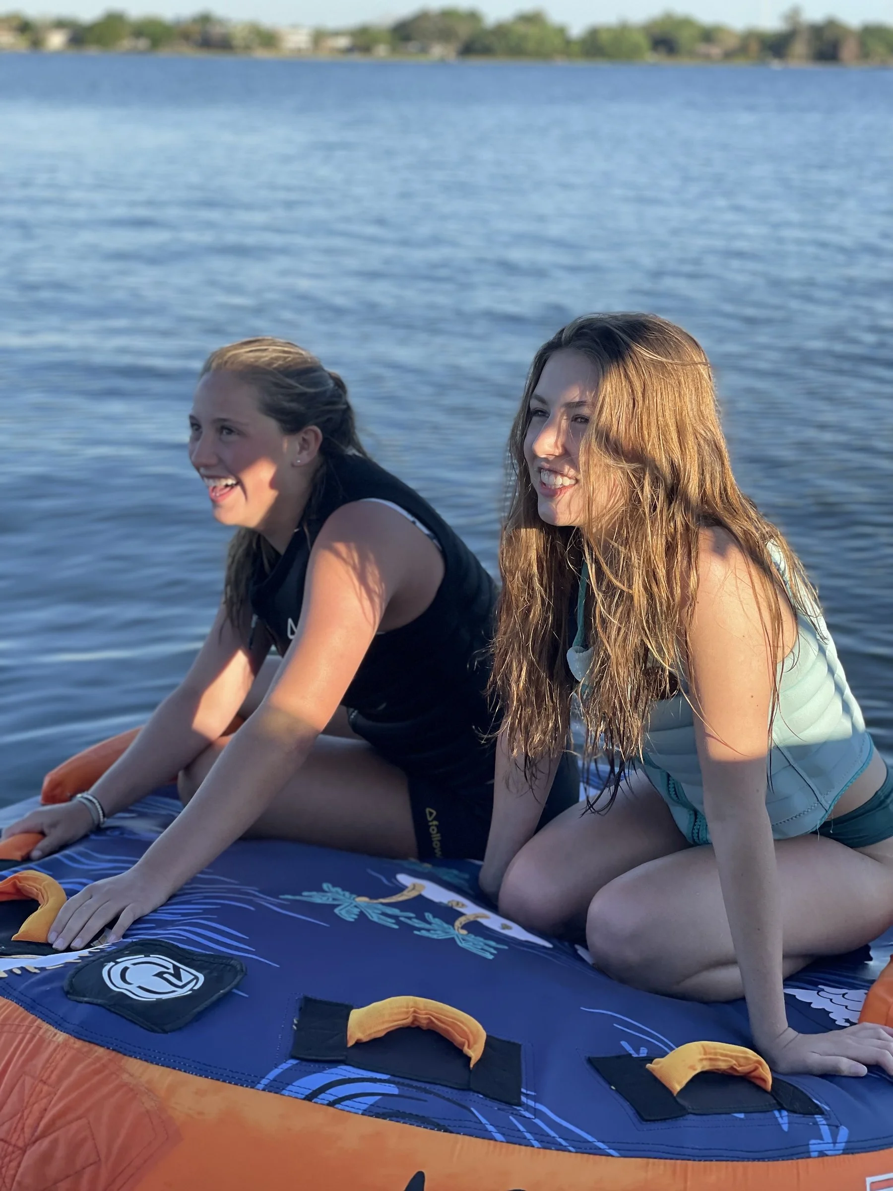 Two friends laughing on a tube on the lake