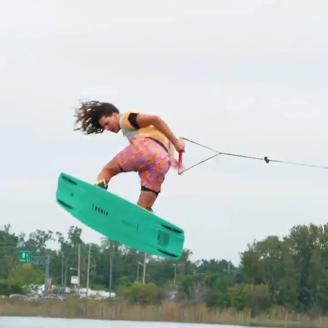 A rider grabbing the board high above the wake